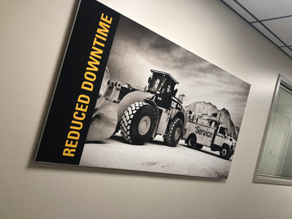 A wall-mounted silicone edge fabric panel featuring a black and white photograph of construction equipment with the text 'REDUCED DOWNTIME' printed on the image.